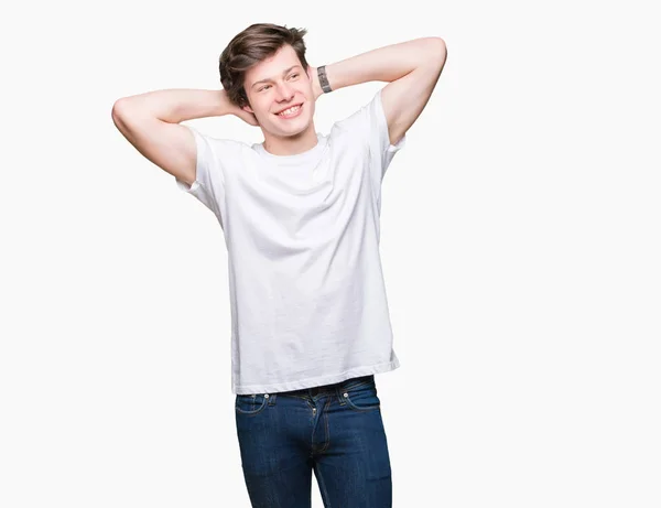 年轻英俊的男人穿着休闲白色 T恤在孤立的背景放松和伸展与手臂和双手背后的头部和颈部 面带微笑的快乐 — 图库照片