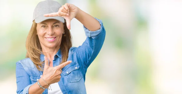 美丽的中年妇女戴着运动帽在孤立的背景微笑框架与手和手指与快乐的脸 创意和摄影理念 — 图库照片