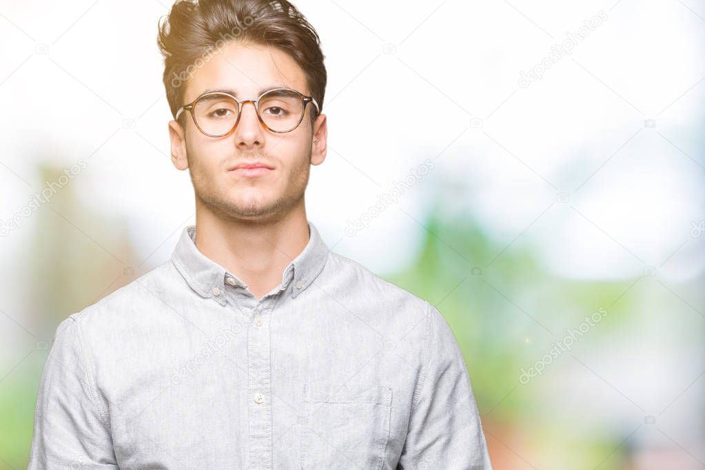 Young handsome man wearing glasses over isolated background Relaxed with serious expression on face. Simple and natural looking at the camera.