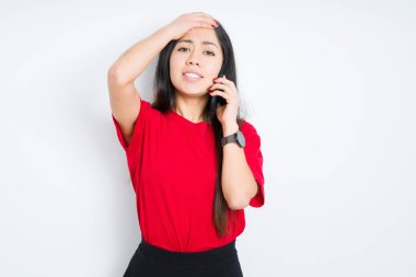 İzole arka plan üzerinde akıllı telefonda konuşan genç esmer kadın, utanç ve sürpriz yüz, kızgın ve sinirli ile şok el ile vurguladı. Korku ve hata için üzgün.