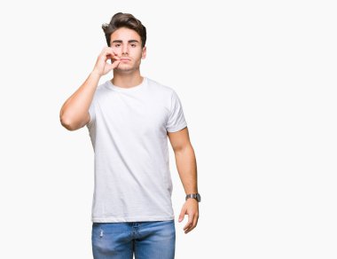 Arka plan ağız beyaz t-shirt üzerinde giyen genç yakışıklı adam izole ve parmak ile ZIP olarak Dudaklarını kapa. Gizli ve sessiz, tabu söz