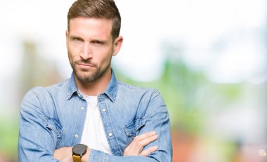 Yakışıklı adam mavi gözleri ve sakal denim ceket şüpheci ve sinir, onaylamayan ifade yüz çapraz kollu giyiyor. Negatif kişi.