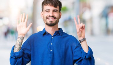 Yakışıklı delikanlı gösterilen ve parmakları ile işaret izole arka plan üzerinde kendinden emin ve mutlu gülümseyerek süre yedi numara.