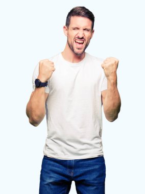 Yakışıklı adam gülümseyerek ve başarı için çığlık casual beyaz t-shirt çok mutlu ve heyecanlı kaldırdı, silah ile kazanan jest yapıyor giyiyor. Kutlama kavramı.