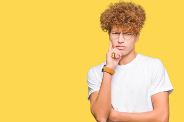 Yakışıklı genç afro saçlı gözlüklü el ile çene düşünme hakkında soru, dalgın ifade üzerine. Düşünceli yüzüyle gülümsüyor. Şüphe kavramı.