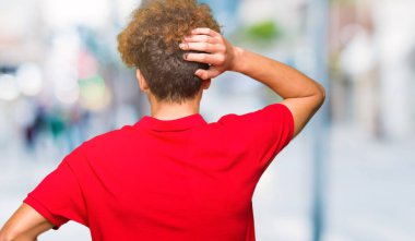 Geriye doğru elle kafasında şüphe hakkında düşünme kırmızı t-shirt giyen afro saçlı Genç yakışıklı adam