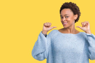 Yüzünde gülümseme ile kendinden emin görünüyorsun, kendini gururlu ve mutlu parmakları ile işaret izole arka plan üzerinde bir kazak giyen genç güzel Afrikalı-Amerikalı kadın.