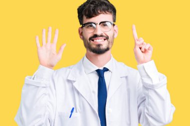 Gösterilen arka plan üzerinde beyaz önlük giyen genç profesyonel bilim adam izole ve parmakları ile işaret kendinden emin ve mutlu gülümseyerek süre 6 numara.