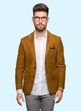 Gevşek ciddi ifade ile yüzünde gözlüklü genç yakışıklı iş adamı. Basit ve doğal kameraya bakıyor.