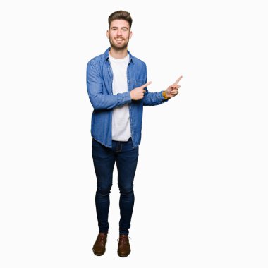 Gülümseyen ve iki elleri ve parmakları ile tarafına işaret kamera bakarak rahat denim ceket giyen genç yakışıklı sarışın adam.