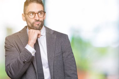 Genç yakışıklı iş adamı çene düşünme hakkında soru, dalgın ifade üzerine el ile izole arka plan üzerinde. Düşünceli yüzüyle gülümsüyor. Şüphe kavramı.