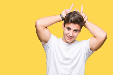 Neşeli gülümseyen komik ve çılgın baş parmaklar ile tavşan kulakları poz izole arka plan üzerinde beyaz t-shirt giyen genç yakışıklı adam