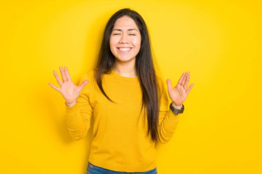 Sarı izole arka plan üzerinde güzel esmer kadın kollarını kaldırdı ve kapalı gözleri heyecanlı çığlık ile başarı için deli ve deli kutluyor. Kazanan kavramı