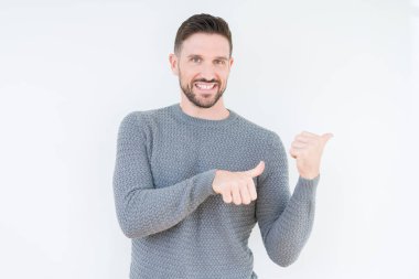 İzole arka plan üzerinde Casual kazak giyen genç yakışıklı adam el ve başparmak ile arka arkaya Işaret, güven gülümseyen