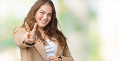 Artı boyutu genç kadın parmaklarını zafer işareti yaparken gösterilen kamera seyir gülümseyen izole arka plan üzerinde kış ceket giyen güzel. İki numaralı.