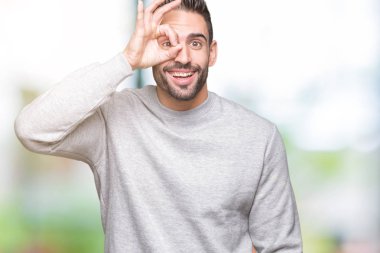 Gülümseyen, parmakları ile mutlu yüz üzerinden seyir göz el ile ok jest yapıyor izole arka plan üzerinde sweatshirt giyen genç yakışıklı adam.
