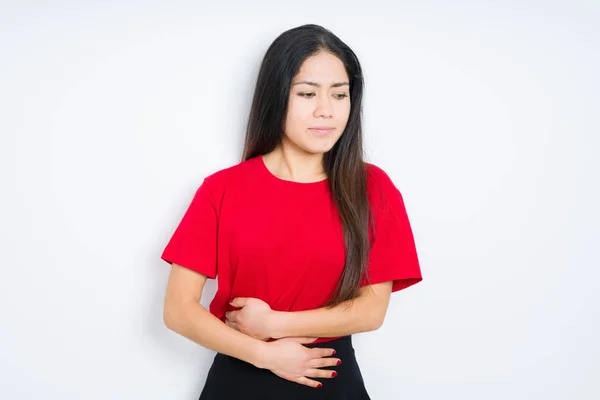 美しいブルネットの女性は 吐き気 痛みを伴う病気の気分が悪いので 胃の上に手で孤立した背景の上に赤いTシャツを着ています 痛い概念 — ストック写真