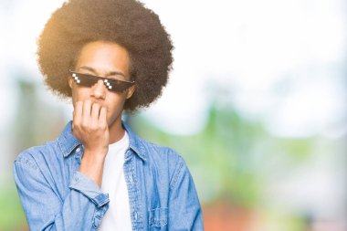 Afro saç giyen haydut hayat gözlük ile genç Afrikalı Amerikalı adam vurguladı ve ağız ısırma çivi elleri ile sinir bakıyor. Anksiyete sorunu.