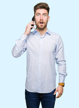 Genç yakışıklı adam iş smartphone bir sürpriz yüz, korkuyor ve heyecanlı korku ifadesi ile şok korkmuş konuşuyor