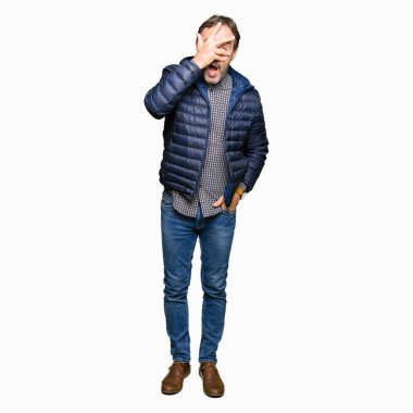 Mahcup ifadeyle parmaklarımın arasından görünen kış ceket yüz ve gözler el ile kapsayan şok bakmak giyen orta yaş yakışıklı adam.