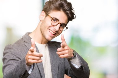 Fotoğraf makinesi ile mutlu ve komik yüz için parmakları işaret izole arka plan üzerinde gözlük takan genç iş adamı. İyi enerji ve vibes.