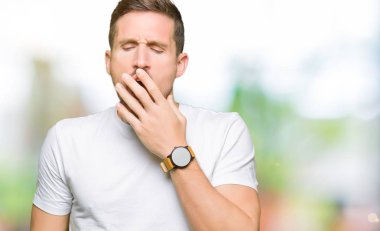 Yakışıklı adam rahat beyaz t-shirt giyen el ağzıyla kapsayan yorgun esneme sıkılmış. Restless ve uyku hali.