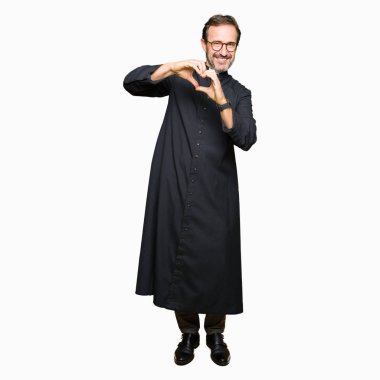 Orta Çağ rahip adam, kalp sembolü ve elleri ile şekil gösteren aşk gülümseyen Katolik Robe giyiyor. Romantik konsept.