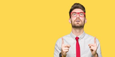 Gözlüklü genç yakışıklı iş adamı şaşırtmak ve yukarıya bakıp parmakları ile işaret şaşırttı ve silah kaldırdı.