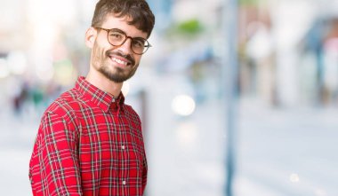 Açık el ile doğal gülümseyen girmek için davet izole arka plan üzerinde gözlük takan genç yakışıklı adam