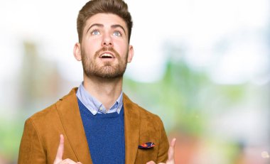 Genç yakışıklı iş adamı şaşırtmak ve yukarıya bakıp parmakları ile işaret şaşırttı ve silah kaldırdı.