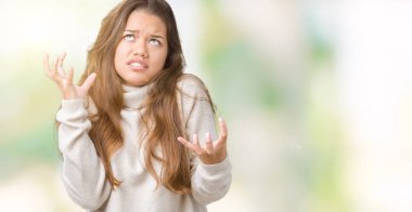 Üzerinde boğazlı kazak giyen genç güzel esmer kadın arka plan deli izole ve deli bağırarak ve agresif ifade ve silah kaldırdı bağırıyor. Hayal kırıklığı kavramı.