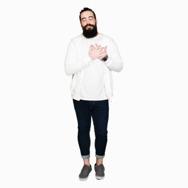 Uzun saç ve sakal ile sportif kazak gülümseyen giyen genç adamla kapalı gözler ve yüzünde minnettar jest ile göğüs üzerinde eller. Sağlık kavramı.