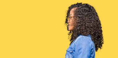 Genç güzel kadın kıvırcık saçlı gözlük tarafına, seyir ile dinlenmek doğal yüz emin gülümseme ile pozuyla profil.