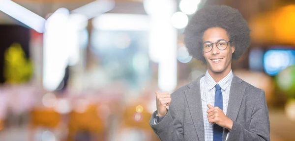 若いアフリカ系アメリカ人ビジネスの男性とアフロの髪を着てメガネ自信の笑みを浮かべて手と親指 裏側を指す — ストック写真