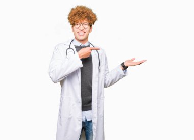 Adam giyen tıbbi kat hayret ve el ile sunulması ve parmak ile işaret ederken kameraya gülümseyen genç yakışıklı Doktor.