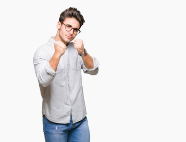 Genç yakışıklı adam gözlük izole arka plan üzerinde yumruk savunma hareketi, kızgın ve üzgün yüz, sorunu korkuyor ile savaşmaya hazır