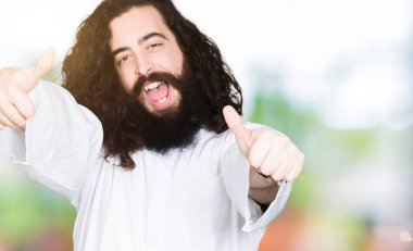 Adam el ile olumlu jest yapıyor onayıyla Isa Mesih kostüm giyen, gülümseyen ve başarı için mutlu kadar başparmak. Kamera bakarak, kazanan jest.