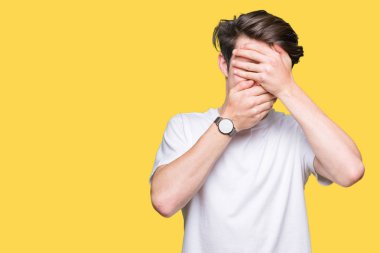 Yakışıklı delikanlı izole arka plan kaplaması gözler ve ağız el ile üzerinden Casual beyaz t-shirt giyen şaşırttı ve şok. Duygu gizleme
