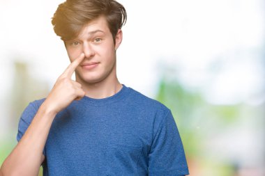 Genç yakışıklı adam izole arka plan üzerinde mavi t-shirt giyen yüz ve burun el parmağı ile işaret, neşeli gülümseyen