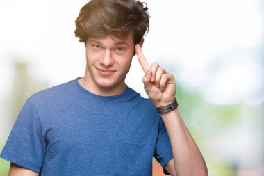 Mavi t-shirt üzerinde izole giyen genç yakışıklı adam arka plan bir parmak, harika bir fikir ya da düşünce, iyi hafıza ile baş gösteren gülen