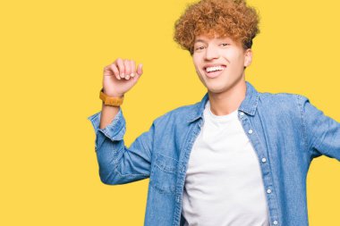 Afro saçlı kot ceket dans mutlu ve neşeli, hareketli rahat ve kendinden emin müzik gülümseyen giyen genç yakışıklı adam