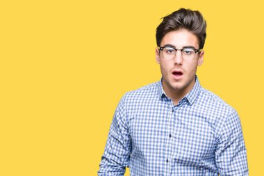 Korkuyor ve şok sürpriz ifade, korku ve heyecan yüz ile izole arka plan üzerinde gözlük takan genç yakışıklı adam.