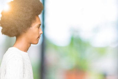 Afro saç giyen kış kazak tarafına, arayan genç Afro-Amerikan adamla sakin ol kendine güvenen gülümseme ile doğal yüz pozuyla profili.