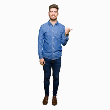 Genç yakışıklı sarışın adam arıyor ve başparmak yanında yukarıyı mutlu yüz ile gülümseyen rahat kot gömlek giymiş.