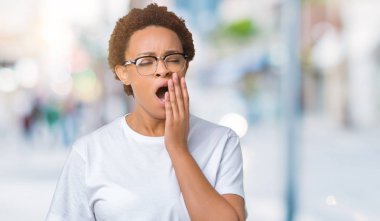 Güzel genç Afro-Amerikan kadın izole arka plan üzerinde gözlük el ağzıyla kapsayan yorgun esneme sıkılmış. Restless ve uyku hali.