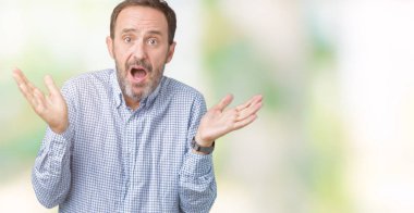 Yakışıklı orta yaş izole arka plan clueless ve şaşkın bir ifadeyle kollar ve eller kaldırdı üzerinde zarif komuta sizde. Şüphe kavramı.