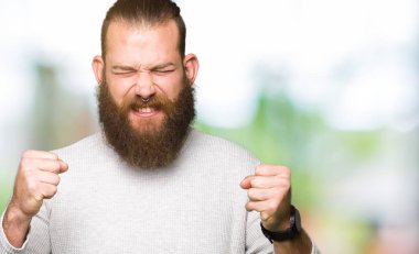 Silah ile başarı için giyiyor rahat kazak heyecanlı genç sarışın adam zafer kutluyor gülümseyen kaldırdı. Kazanan kavramı.