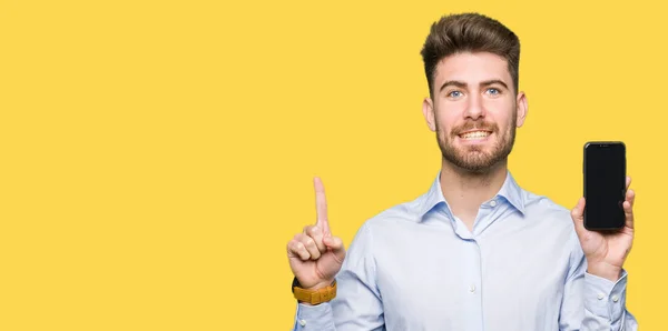 Junger Gutaussehender Mann Zeigt Smartphone Bildschirm Überrascht Mit Einer Idee — Stockfoto