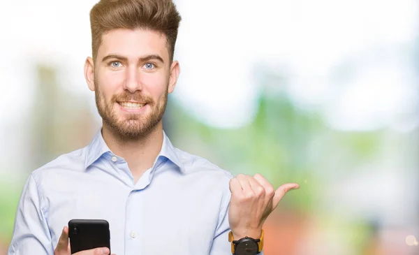 年轻英俊的男人业务使用智能手机指指点点 用拇指显示在一边 快乐的脸微笑着 — 图库照片