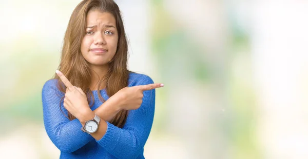 年轻美丽的黑发女人穿着蓝色毛衣在孤立的背景指向双方用手指 不同的方向不同意 — 图库照片